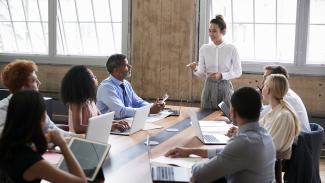 A person speaks to a group at a table.